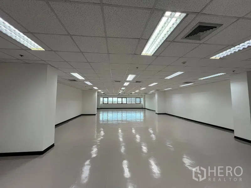 Office Space for rent or sale - Spacious open-plan office floor with drop ceiling, fluorescent lights, and a wall of windows in Ekkamai, Bangkok.