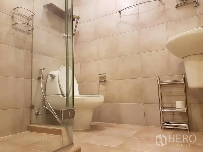 คอนโด ให้เช่าในWatthana, Bangkok - ห้องน้ำที่สองพร้อมฝักบัวกระจก โถสุขภัณฑ์ และอ่างล้างหน้าโถตั้งพื้น ปูกระเบื้องสีเบจ