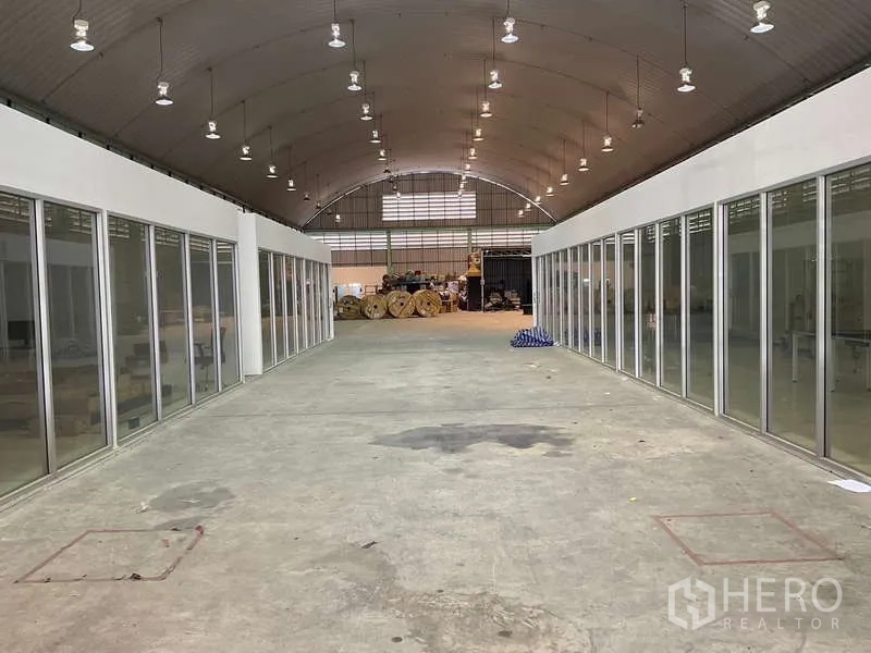 货栈 出租在Lak Si, Bangkok - 仓库内部高挑拱顶，中间通道，两侧为玻璃隔断办公区。