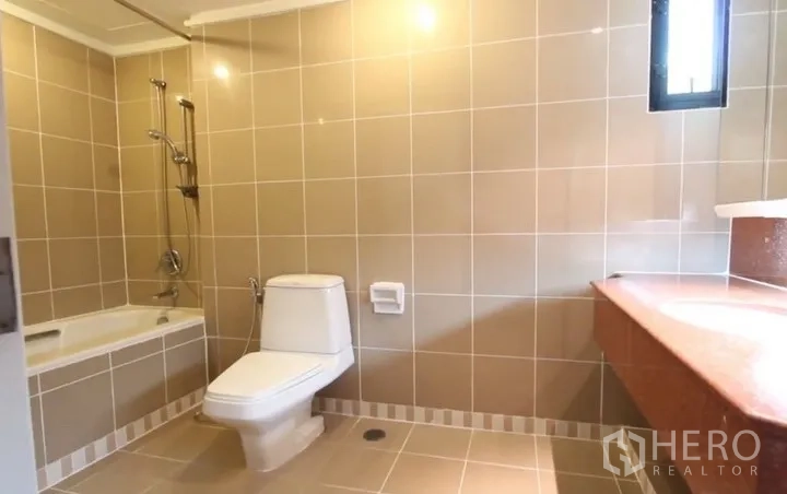 房间 出租在Khlong Toei, Bangkok - 米色瓷砖浴室，带浴缸与淋浴、坐便器、长台面及小窗。