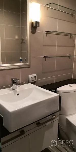 Condominium for rent in Sathon, Bangkok - Modern tiled bathroom featuring a square basin, mirror and shelving.