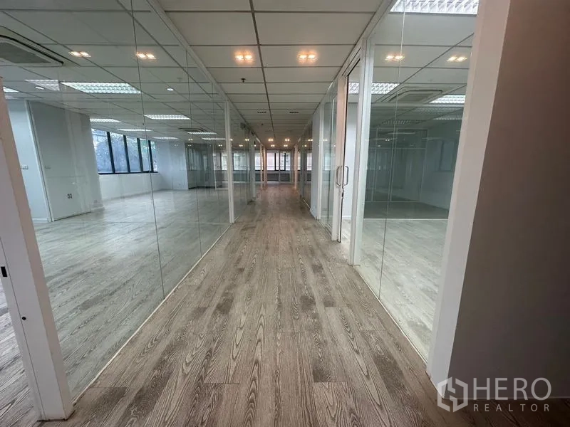 办公空间 出租在Din Daeng, Bangkok - 走廊两侧为玻璃会议室，嵌灯照明。