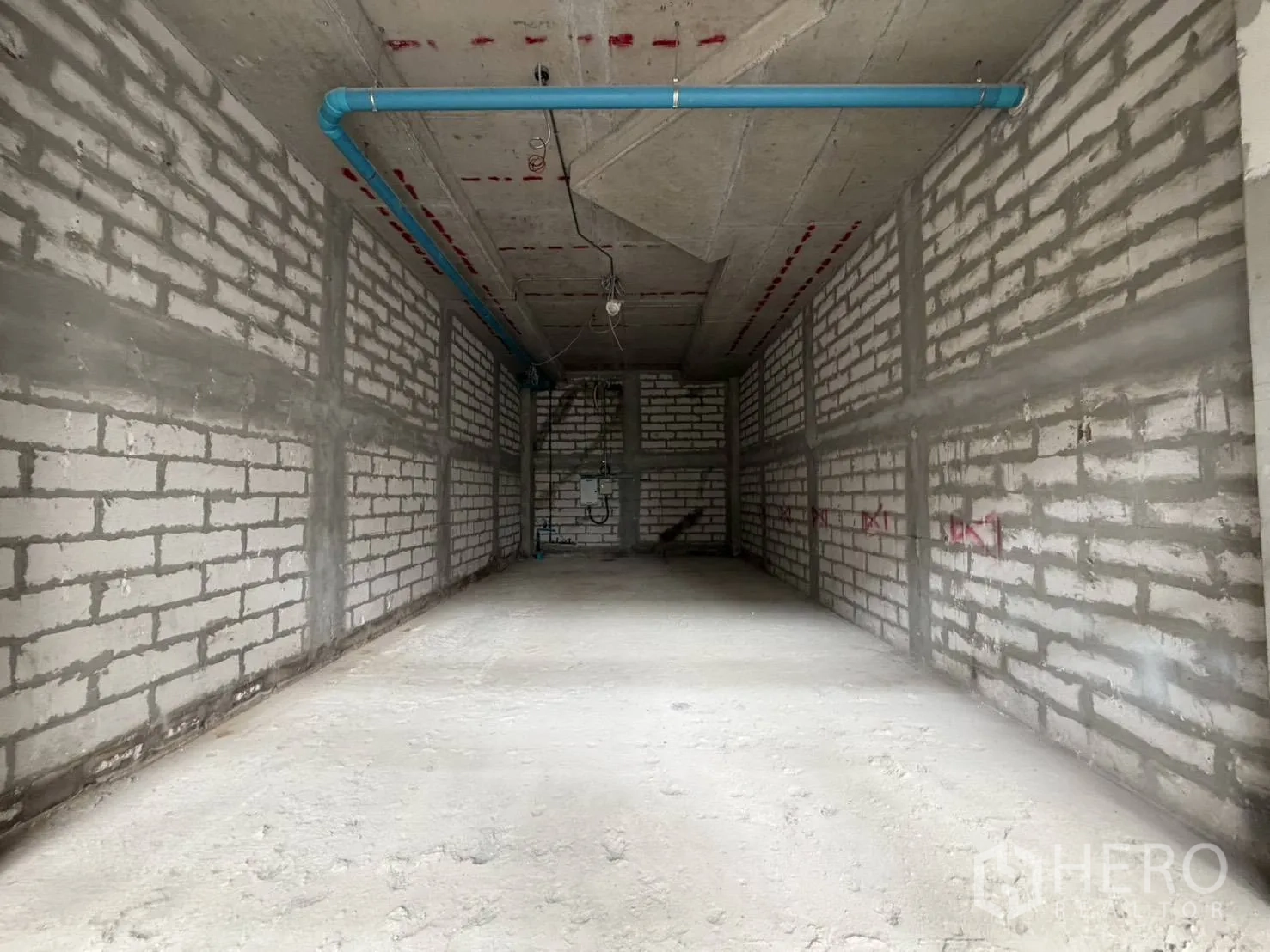 Retail Space for rent in Khlong Toei, Bangkok - Long, rectangular open-plan interior with utility points and blue water pipes.