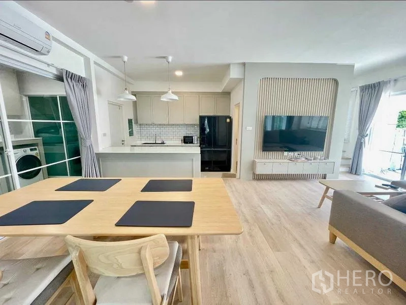 联排别墅 出租或出售在Prawet, Bangkok - 开放客餐区，餐桌、吊灯、厨房与电视墙一览无余。