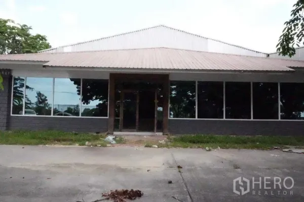 Warehouse for rent in Phra Nakhon Si Ayutthaya - Front facade with wide glass windows, main entrance and concrete driveway.