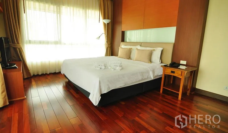 อพาร์ทเมนท์ ให้เช่าในKhlong Toei, Bangkok - ห้องนอนกว้าง เตียงคิง โคมไฟยืน ชั้นวางทีวี และพื้นไม้ขัดเงา ในกรุงเทพฯ