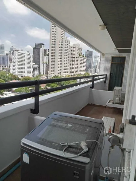 Condominium for rent in Watthana, Bangkok - Balcony utility area with washing machine and city view behind railings.