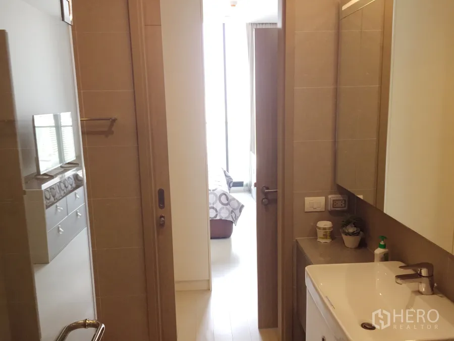 Condominium for rent in Pathum Wan, Bangkok - Modern bathroom with vanity and sliding door opening to a bright bedroom in a Bangkok condo.