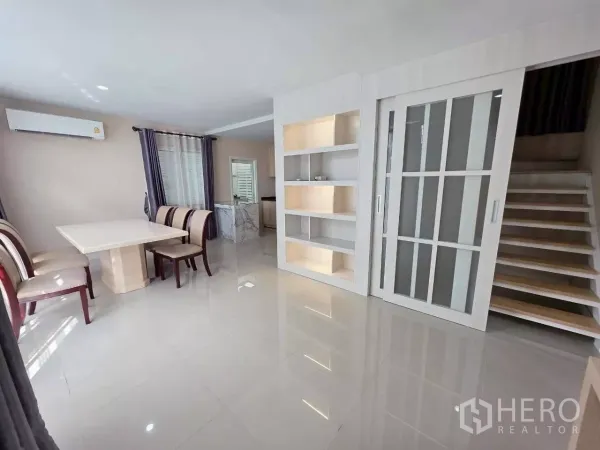Detached House for rent or sale in Samut Prakan - Bright living and dining area with glossy tile floors, built-in shelving and stairs.