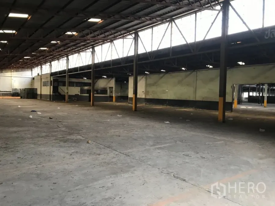 Land for rent in Phra Pradaeng, Samut Prakan - Spacious warehouse interior with steel truss roof, concrete floor and mezzanine office on an industrial site.