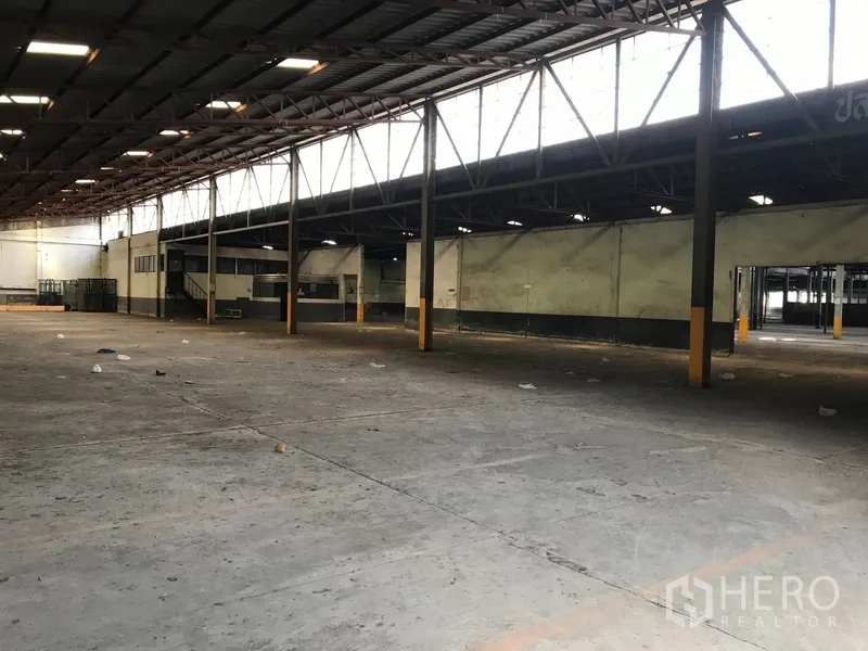 Land for rent in Phra Pradaeng, Samut Prakan - Spacious warehouse interior with steel truss roof, concrete floor and mezzanine office on an industrial site.