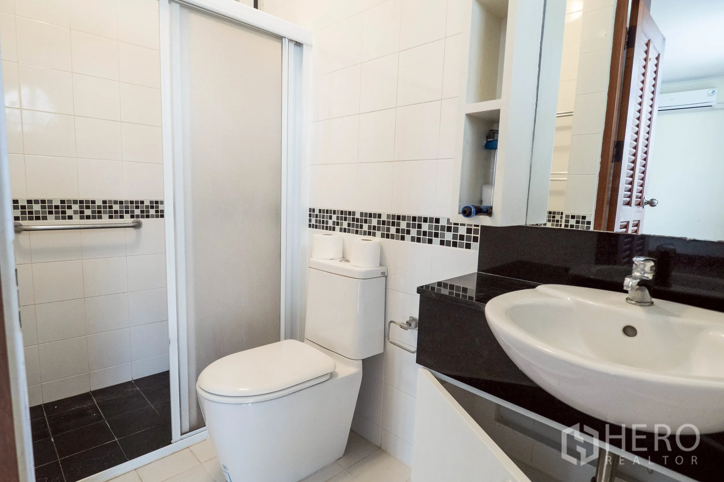 Townhouse for rent in Khlong Toei, Bangkok - Bright white-tiled bathroom with mosaic accent and enclosed shower.