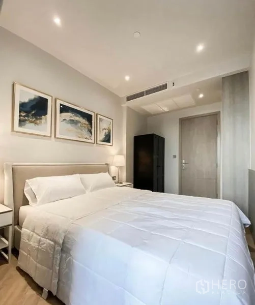 Condominium for rent in Din Daeng, Bangkok - Bedroom showing bed, artwork and wardrobe in soft neutral tones.