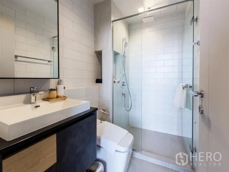 公寓 出租在Chatuchak, Bangkok - 现代卫浴，宽大台盆，玻璃淋浴间与白色地铁砖。