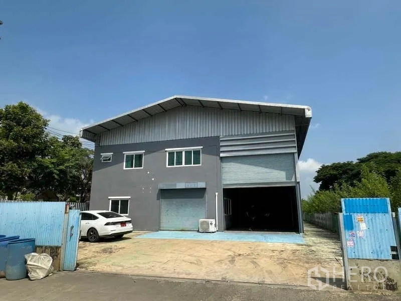 货栈 出租在Pathum Thani - 街景外观，仓库正面、围栏大门与停车位