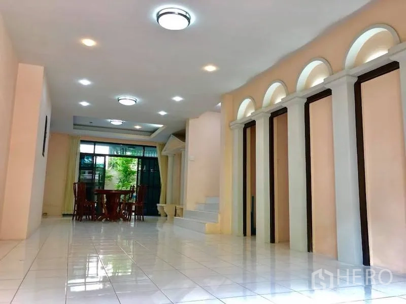 Townhouse for rent in Watthana, Bangkok - Long living-dining room with recessed lights, arched niches and garden-view glass doors.