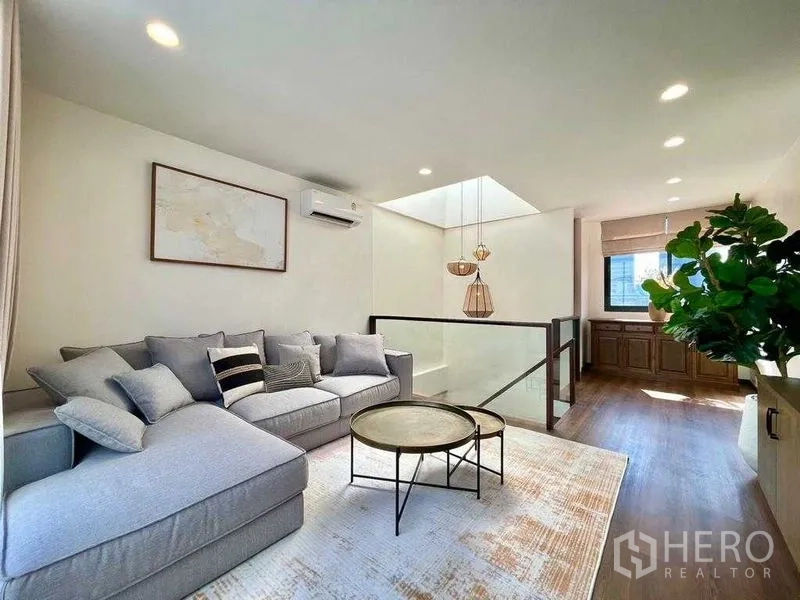 Detached House for rent in Bang Rak, Bangkok - Upper lounge with skylight, sofa seating and glass stair balustrade.