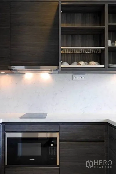 Condominium for rent or sale in Watthana, Bangkok - Close-up of built-in kitchen with induction hob, microwave and dish rack.