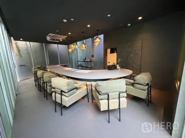 Retail Space for rent in Khlong Toei, Bangkok - Open‑plan retail lounge with a U‑shaped counter, padded chairs, and globe pendant lighting.