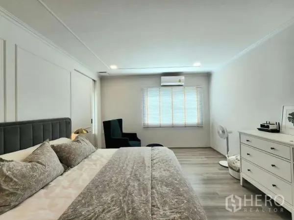 Detached House for rent or sale in Bang Phli, Samut Prakan - Master bedroom angle showing dresser, lounge chair and window air conditioning.