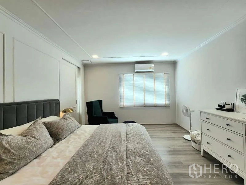 Detached House for rent or sale in Bang Phli, Samut Prakan - Master bedroom angle showing dresser, lounge chair and window air conditioning.