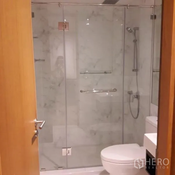 Condominium for sale in Sathon, Bangkok - Bathroom featuring a glass‑enclosed shower with rain and handheld heads and marble‑look tiles.