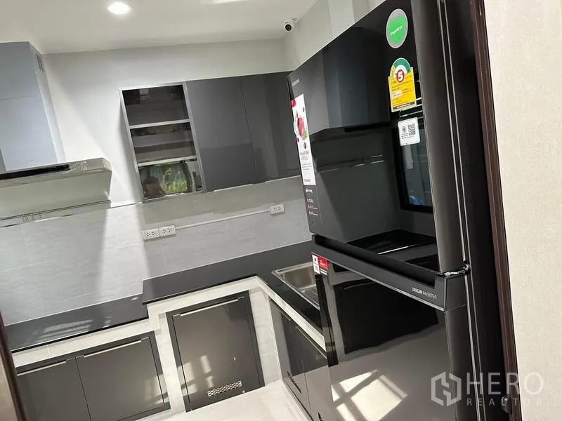 บ้าน ขายในSaphan Sung, Bangkok - ครัวบิวท์อินรูปตัว U ตู้เงาและตู้เย็นสีดำ