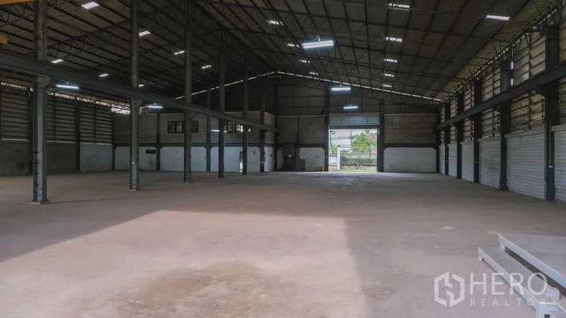 Factory for rent in Bang Phli, Samut Prakan - View across the factory floor toward the entry gate and attached office block.