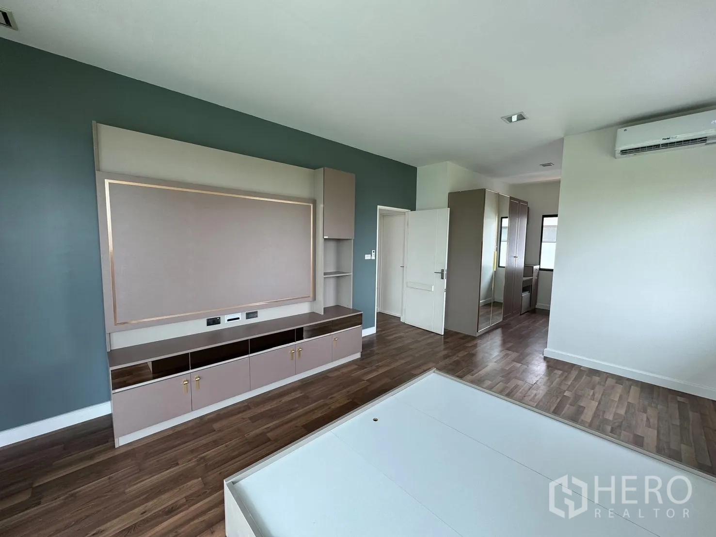 Detached House for rent in Prawet, Bangkok - Spacious bedroom with built-in TV wall, wardrobe, wood floors and air conditioner.