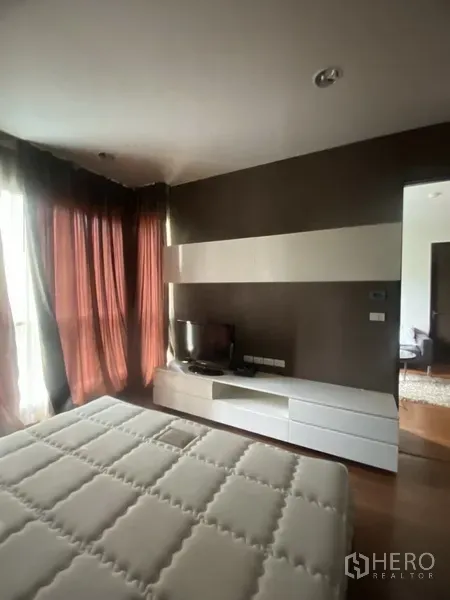 คอนโด ให้เช่าในPathum Wan, Bangkok - มุมห้องนอนพร้อมตู้วางทีวีและชั้นเก็บของ ผ้าม่านสูงจรดพื้น และพื้นไม้โทนอุ่น