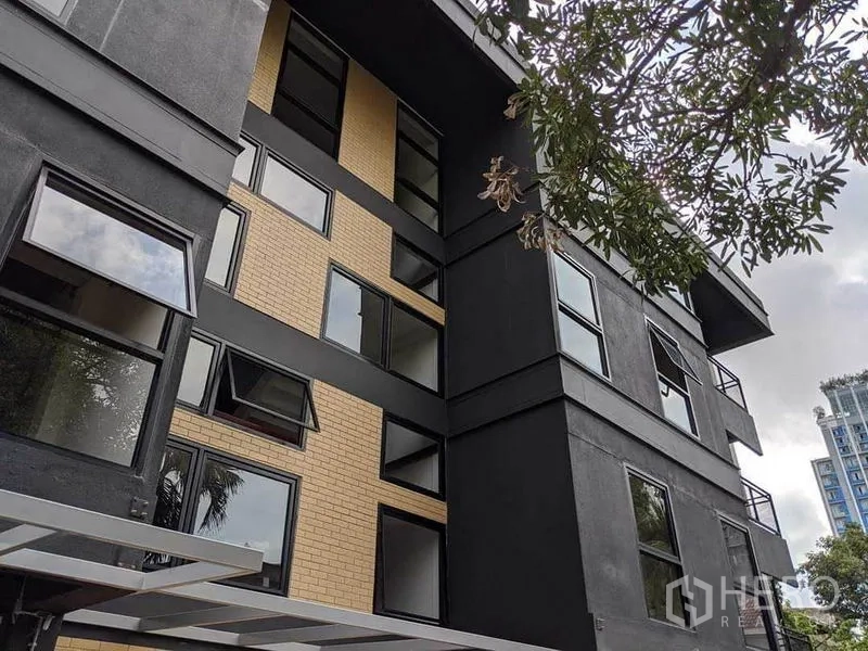 带办公室的家 出租或出售在Phaya Thai, Bangkok - 现代中高层建筑外立面，黑色与米色砖墙，大量窗户。