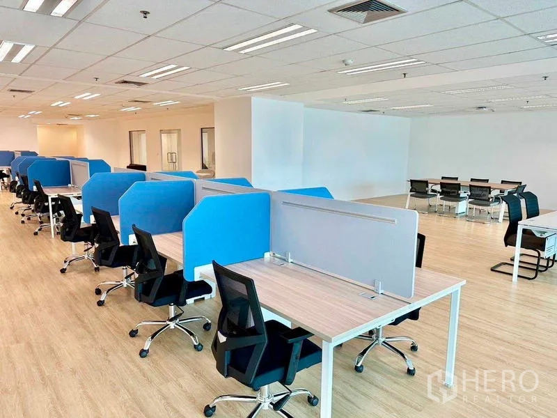 Office Space for rent - Row of bench desks with blue and gray acoustic panels beside a conference table zone.