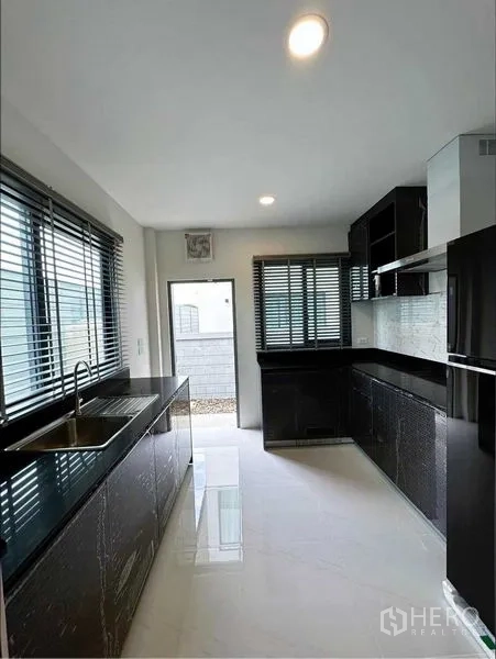 Detached House for rent or sale in Bang Phli, Samut Prakan - Sleek closed kitchen with black stone countertops, ample cabinets and windows.