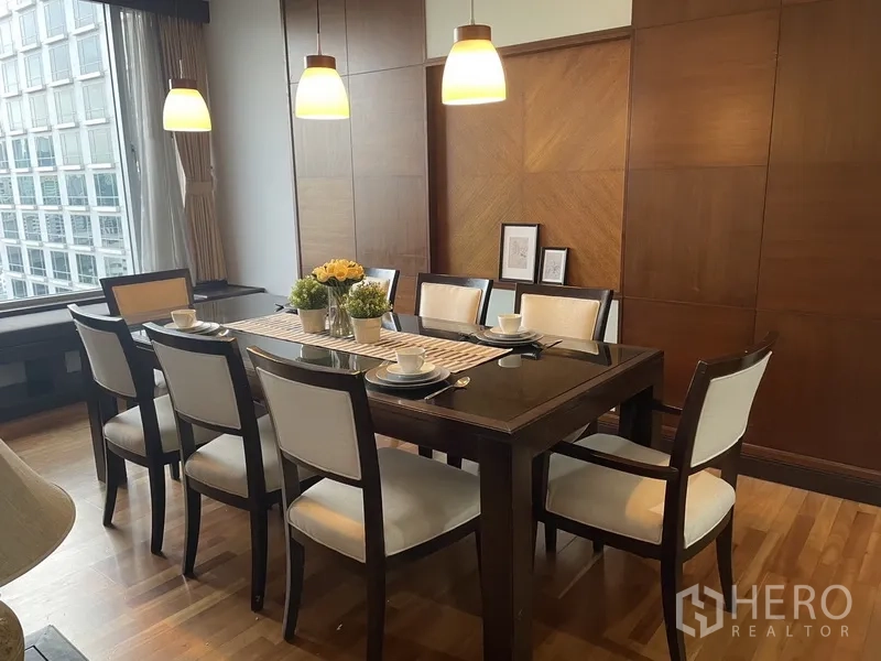 Condominium for rent or sale in Pathum Wan, Bangkok - Eight‑seat dining room with dark wood table, upholstered chairs, warm wall paneling and large window with city view.