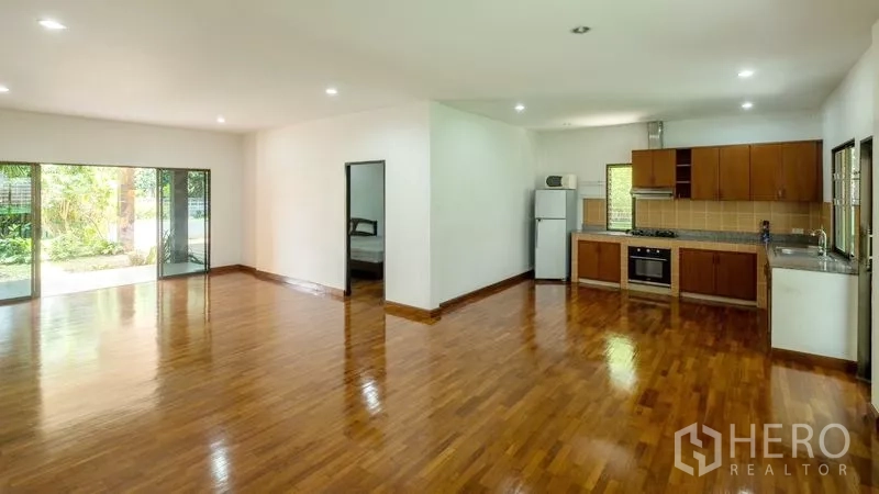 Detached House for sale in Bang Lamung, Chon Buri - L-shaped European kitchen with built-in oven beside a large living space and sliding doors.