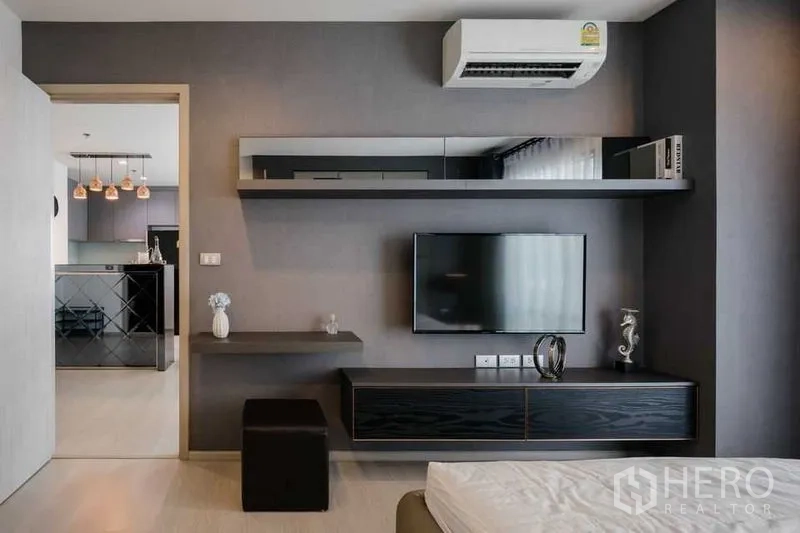 คอนโด ให้เช่าในKhlong Toei, Bangkok - ผนังทีวีพร้อมชั้นแขวนในห้องนอน มองเห็นครัวและโคมไฟห้อย