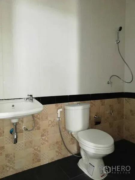 Warehouse for rent in Mueang Samut Sakhon, Samut Sakhon - Clean bathroom with toilet, wall-mounted sink and shower set inside the warehouse.