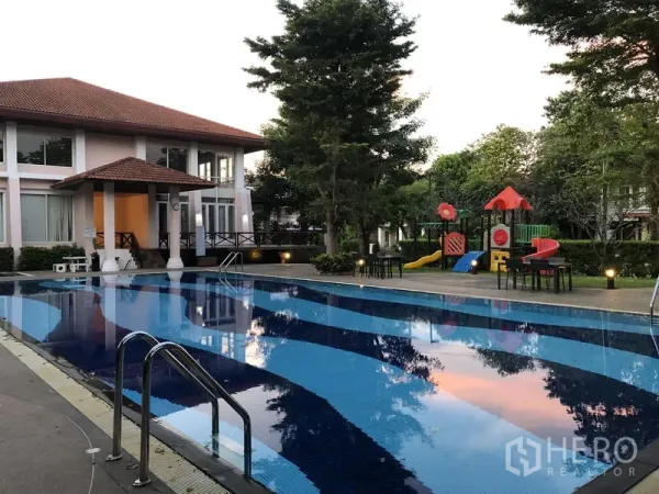 Detached House for rent in Wang Thonglang, Bangkok - Community swimming pool beside a clubhouse with trees and a children’s playground in the estate.