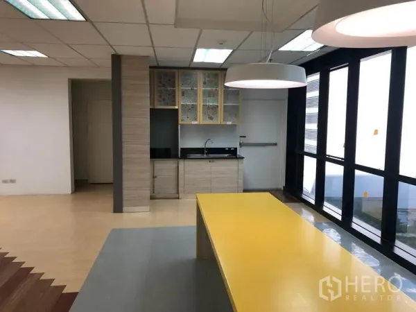 办公空间 出租在Bang Na, Bangkok - 茶水间配长黄色吧台、水槽和高窗采光。