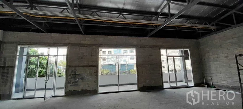 零售空间 出租在Khlong Toei, Bangkok - 店铺内部设落地玻璃推门，连接阳台，可见城市景观。