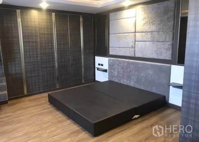 คอนโด ให้เช่าในKhlong Toei, Bangkok - ห้องนอนใหญ่กว้างขวางพร้อมเตียงยกพื้น ผนังตกแต่ง และตู้เสื้อผ้าเต็มความสูง