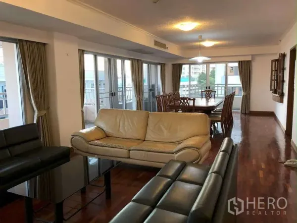 公寓 出租在Sathon, Bangkok - 宽敞的客餐厅一体空间，皮沙发、木地板与落地窗相连的阳台，位于沙吞公寓内