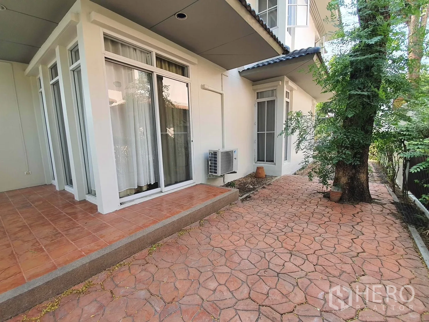 独栋房屋 for rent in Wang Thonglang, Bangkok - 侧院露台铺砖并设推拉玻璃门，旁有遮荫步道与成树。