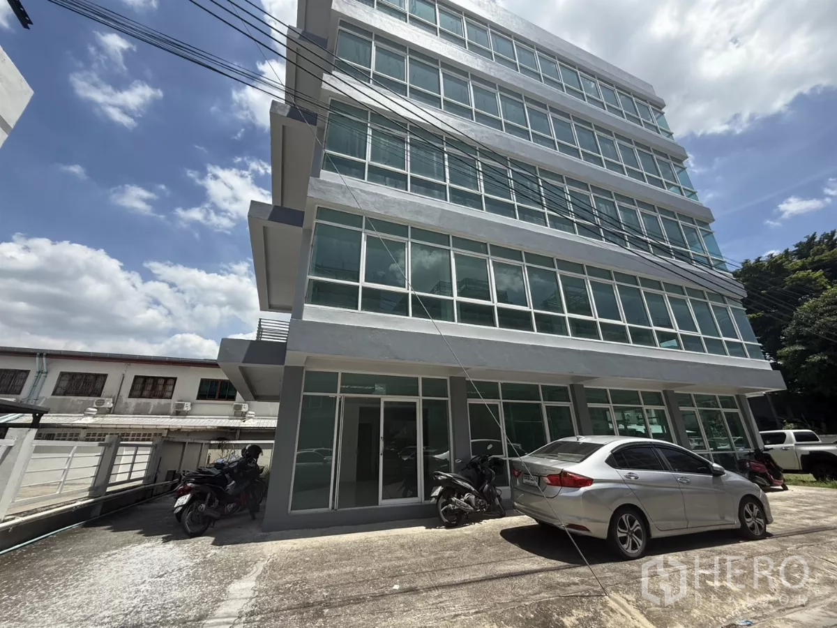 สำนักงาน ให้เช่าในBueng Kum, Bangkok - มุมมองด้านข้างของอาคารสำนักงานสมัยใหม่หลายชั้นและทางจอดรถ