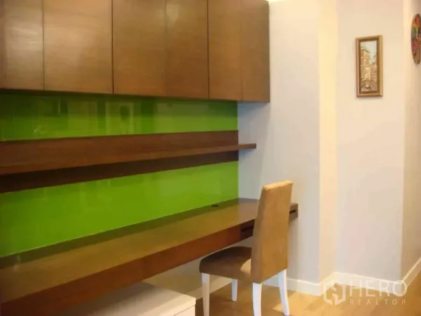 Condominium for rent in Watthana, Bangkok - Built-in home office desk with wood cabinets and a lime-green feature wall.