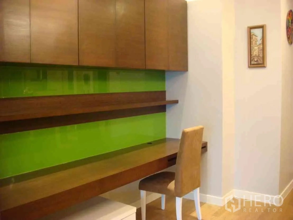 Condominium for rent in Watthana, Bangkok - Built-in home office desk with wood cabinets and a lime-green feature wall.