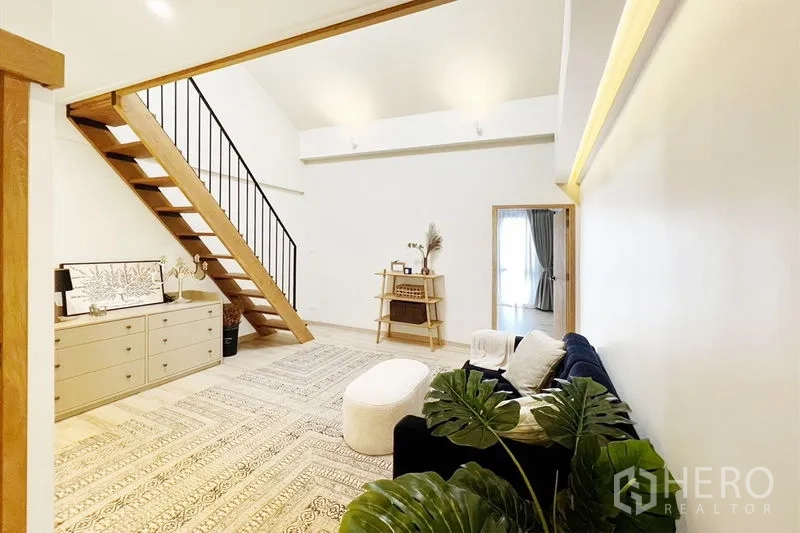 联排别墅 出租在Khlong Toei, Bangkok - 挑高家庭厅，夹层楼梯与沙发座椅，简约温馨。