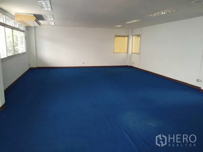 Warehouse for rent in Bang Phli, Samut Prakan - Spacious office area with blue carpet flooring, multiple light fixtures and wall windows.