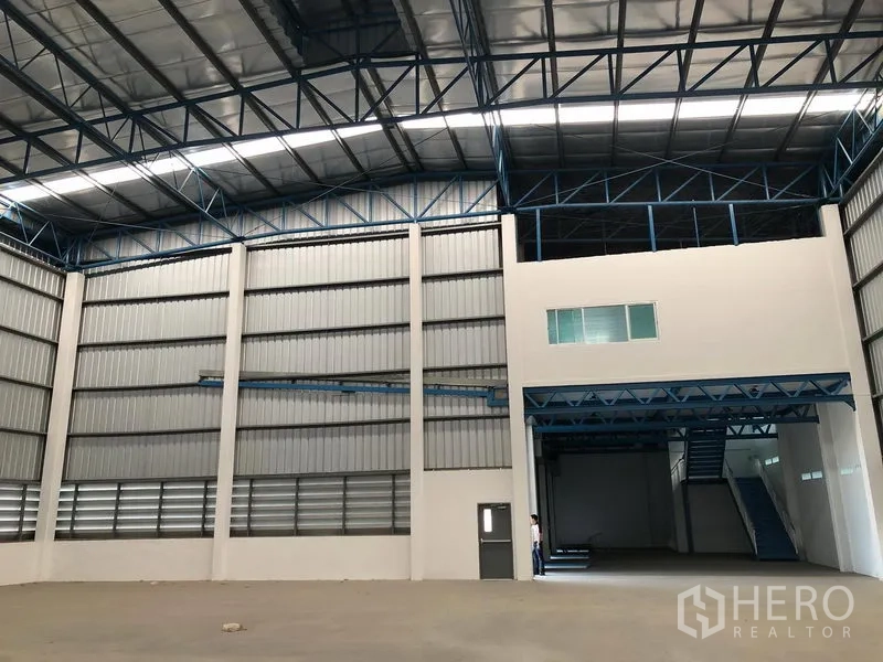 Warehouse for rent in Lat Krabang, Bangkok - Warehouse interior showing mezzanine office, wide roller door and blue steel structure.