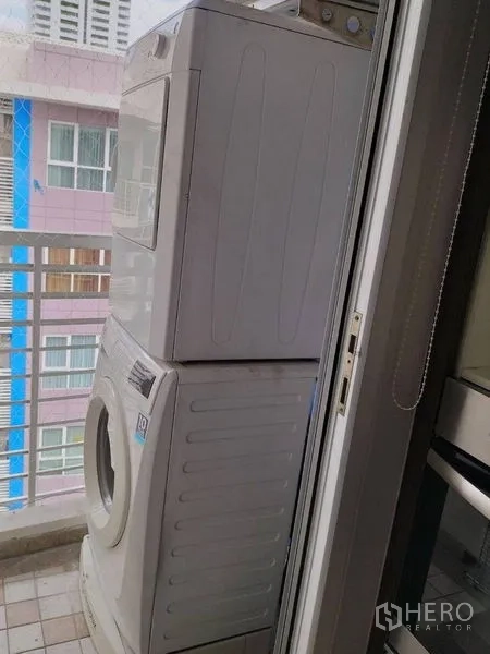 Condominium for rent in Watthana, Bangkok - Stacked washer and dryer on the balcony with city view railings.